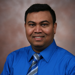 A smiling man in a blue shirt and tie