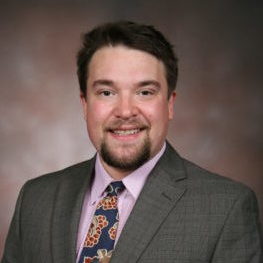 A man wearing a suit and tie smiling at the camera